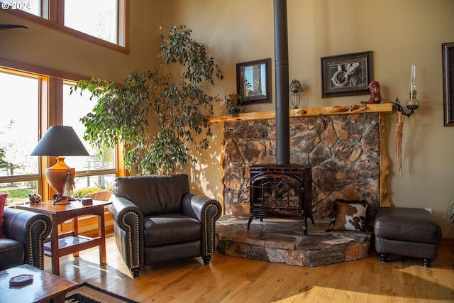 living room featuring plenty of natural light, a wood stove, a high ceiling, and light hardwood / wood-style flooring