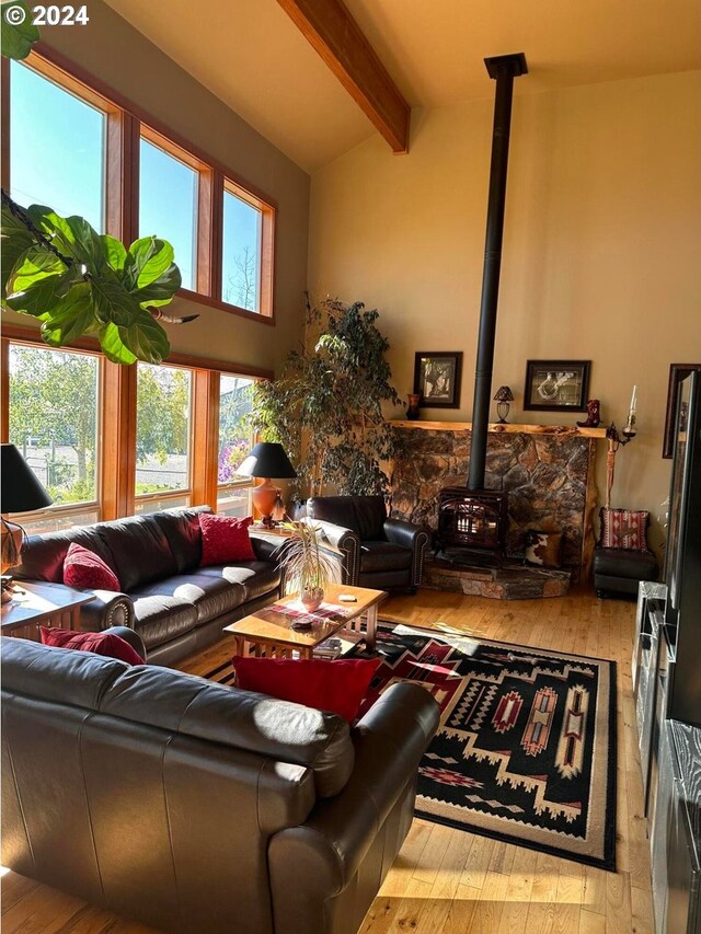 living room with lofted ceiling with beams, light wood-type flooring, and a wood stove