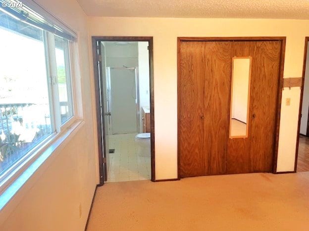 unfurnished bedroom featuring connected bathroom, a textured ceiling, and carpet flooring