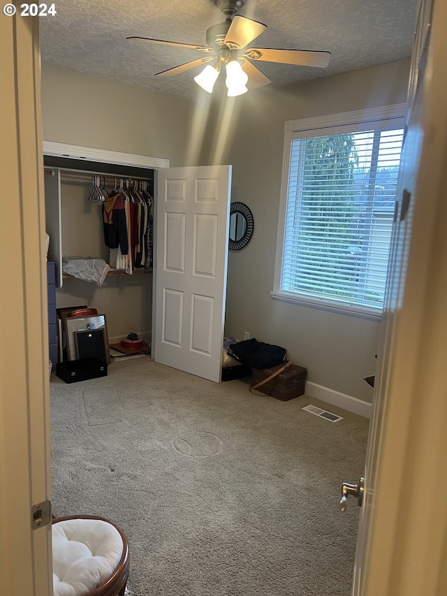 bedroom featuring ceiling fan, a closet, carpet, and a textured ceiling