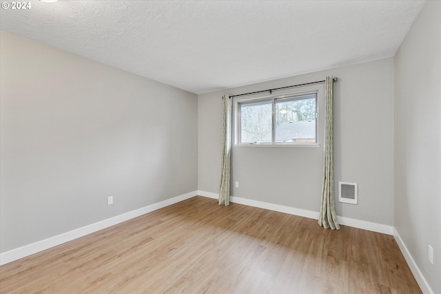 empty room with a textured ceiling and light wood-type flooring