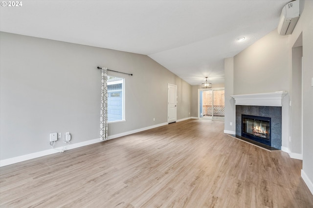 unfurnished living room featuring a wall mounted air conditioner, light wood-type flooring, a fireplace, and vaulted ceiling