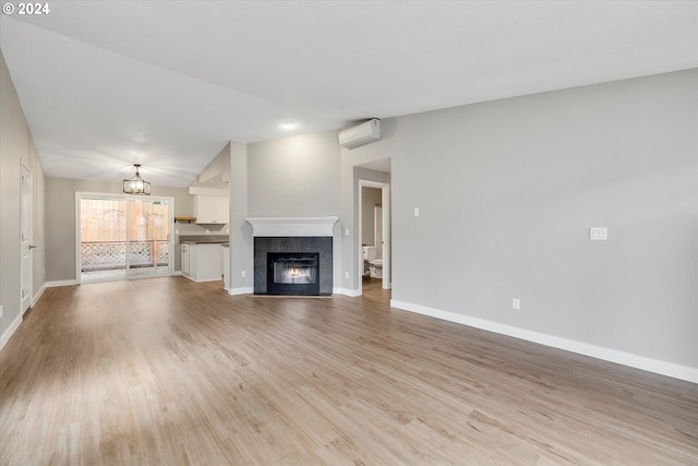 unfurnished living room featuring light wood-type flooring, an AC wall unit, a fireplace, and vaulted ceiling