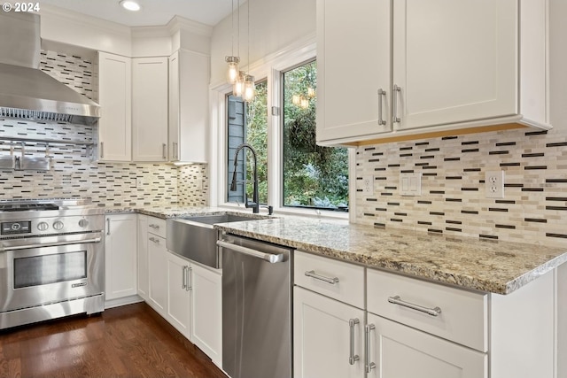 kitchen featuring decorative backsplash, white cabinets, pendant lighting, wall chimney exhaust hood, and stainless steel appliances