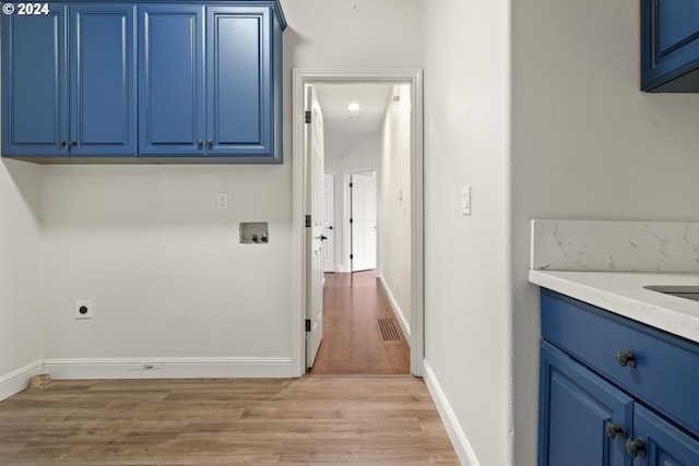 laundry area with hookup for a washing machine, light hardwood / wood-style floors, cabinets, and hookup for an electric dryer