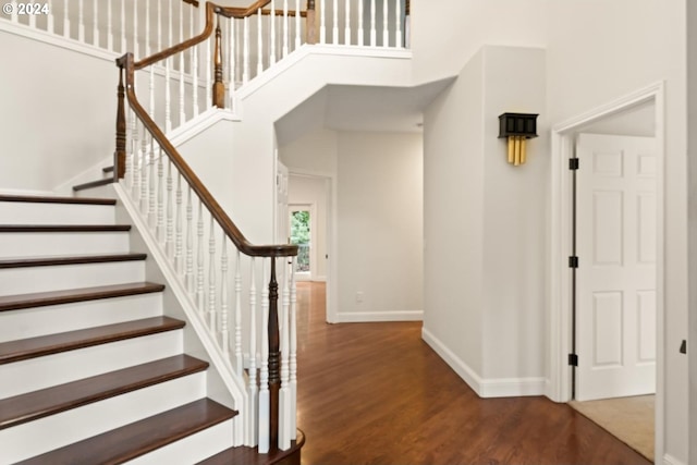 stairs with hardwood / wood-style flooring and a towering ceiling