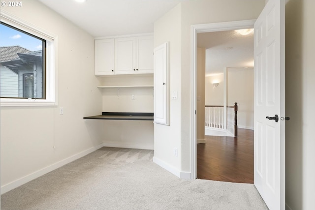 interior space with built in desk and light carpet