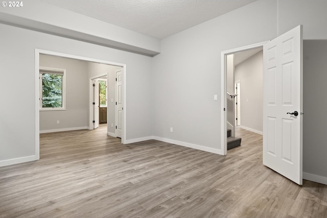 empty room with light hardwood / wood-style floors and a textured ceiling