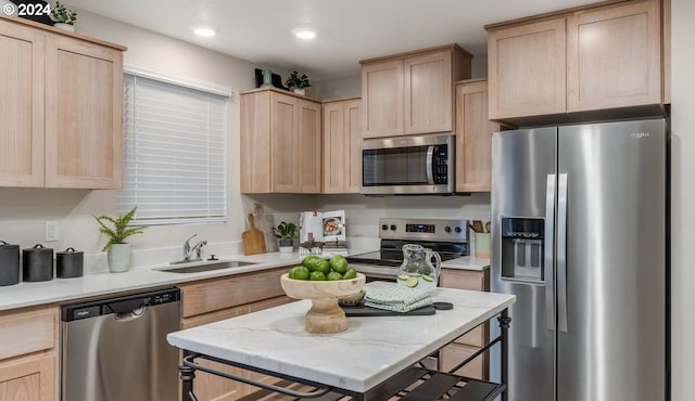 kitchen with a sink, appliances with stainless steel finishes, light brown cabinetry, and light countertops