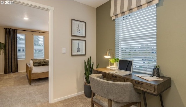 office featuring baseboards and light carpet