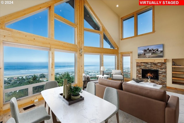 dining space with high vaulted ceiling, a water view, and a fireplace