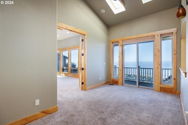 carpeted spare room with a water view and lofted ceiling with skylight