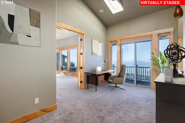 office area with a water view, light colored carpet, lofted ceiling with skylight, and a healthy amount of sunlight