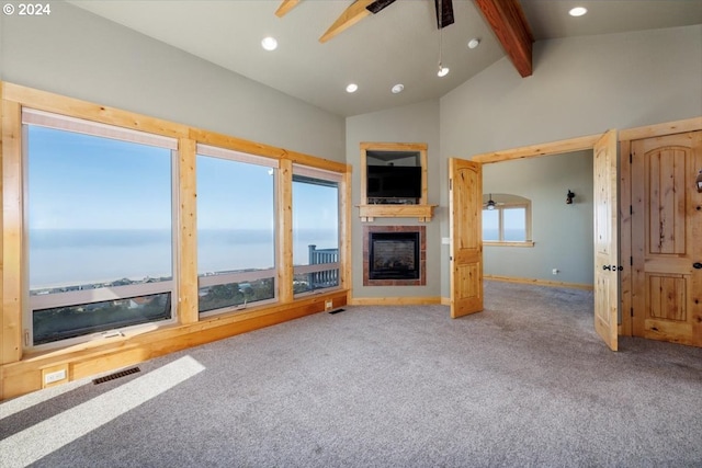 unfurnished living room with ceiling fan, lofted ceiling with beams, carpet, and a large fireplace