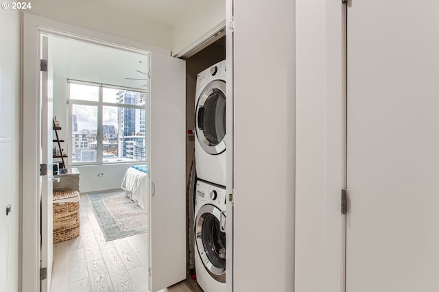 washroom featuring light hardwood / wood-style floors and stacked washing maching and dryer