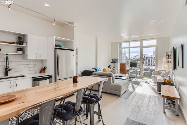 kitchen featuring sink, tasteful backsplash, light hardwood / wood-style floors, white cabinets, and appliances with stainless steel finishes