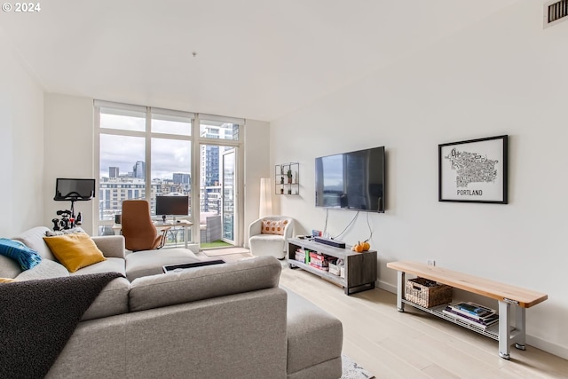 living room with light wood-type flooring and floor to ceiling windows