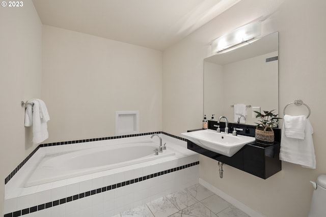 bathroom featuring toilet, sink, and a relaxing tiled tub