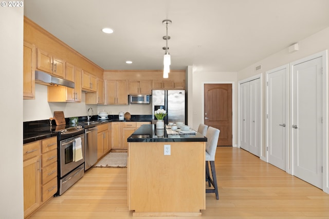 kitchen with stainless steel appliances, light hardwood / wood-style floors, a center island, and decorative light fixtures