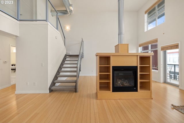 unfurnished living room with a wealth of natural light, wood-type flooring, and a high ceiling