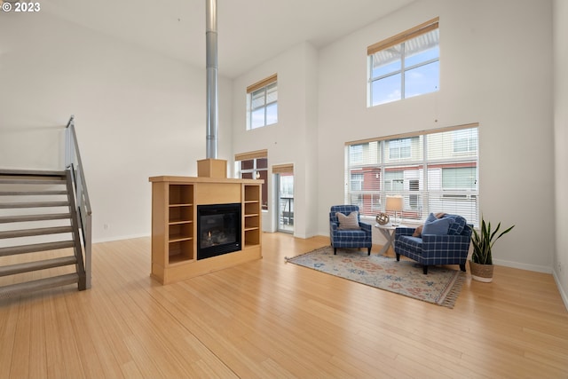 living room featuring light wood-type flooring and a towering ceiling