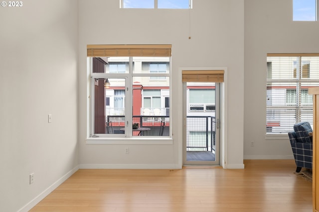 spare room featuring a towering ceiling, light hardwood / wood-style flooring, and a wealth of natural light