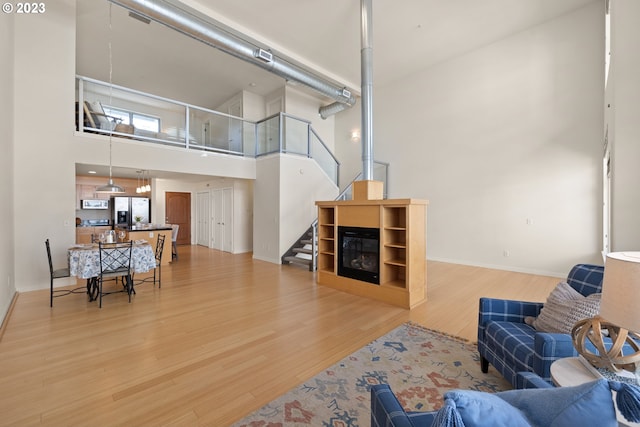 living room with light wood-type flooring and a towering ceiling