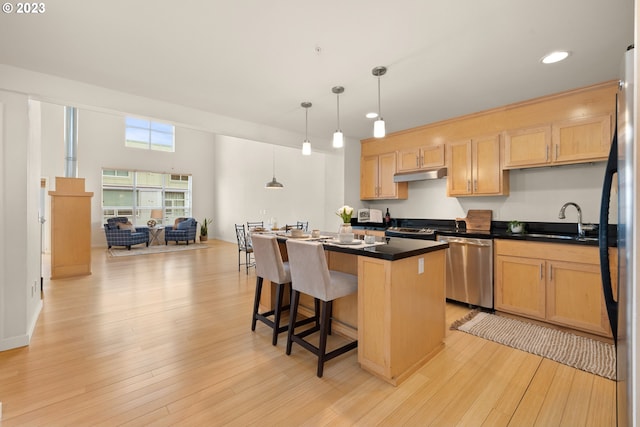 kitchen with light wood-type flooring, a center island, appliances with stainless steel finishes, and hanging light fixtures