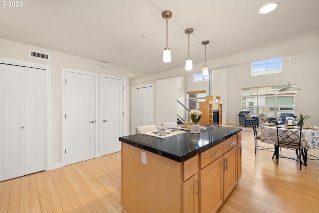 kitchen featuring light wood-type flooring, a fireplace, a kitchen island, and pendant lighting