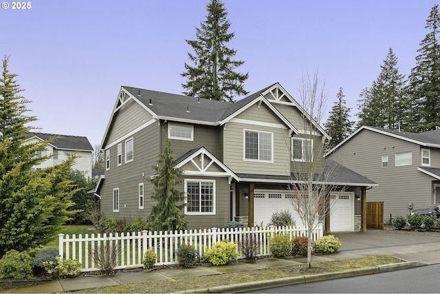 craftsman-style house with a fenced front yard, driveway, and an attached garage