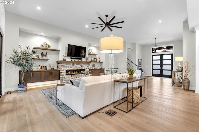 living room with french doors, a fireplace, built in shelves, and light wood-type flooring