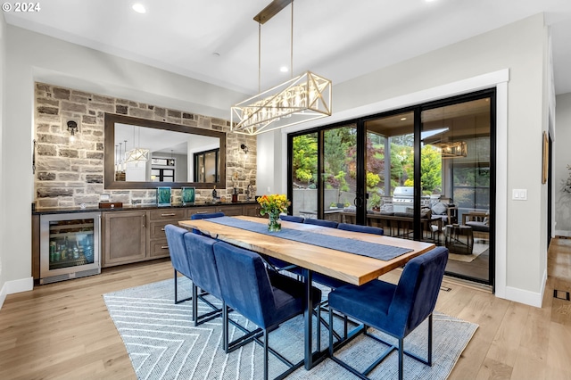 dining room featuring french doors, indoor bar, beverage cooler, and light hardwood / wood-style flooring