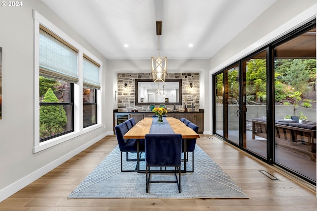 dining space featuring an inviting chandelier, light hardwood / wood-style flooring, and wine cooler