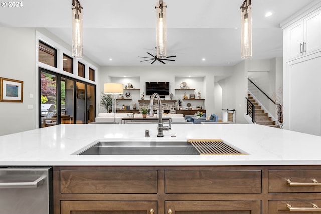 kitchen with pendant lighting, white cabinetry, sink, stainless steel dishwasher, and a center island with sink