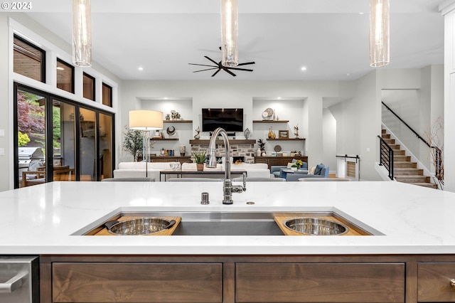 kitchen featuring a kitchen island with sink, hanging light fixtures, light stone countertops, and sink