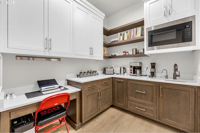 kitchen featuring built in microwave, sink, light hardwood / wood-style floors, and white cabinets