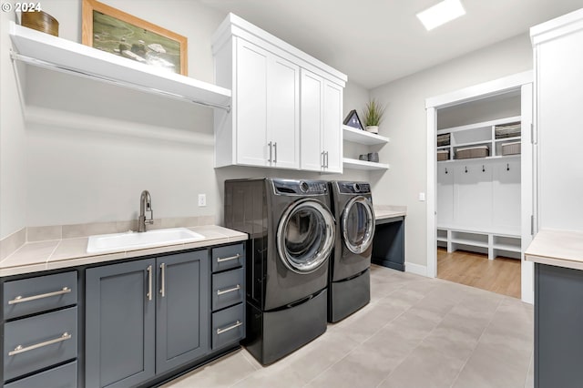 laundry room with cabinets, separate washer and dryer, sink, and light tile patterned floors