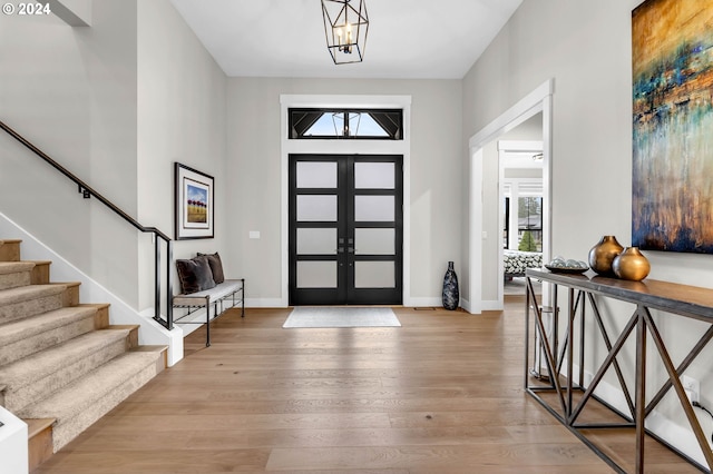 entrance foyer with a notable chandelier, light hardwood / wood-style floors, and french doors