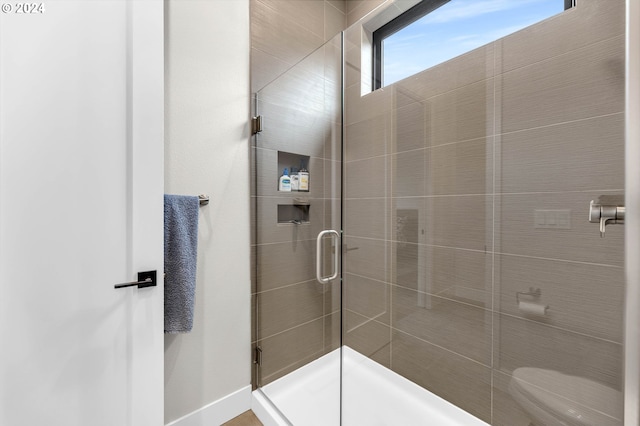 bathroom featuring a shower with door and toilet