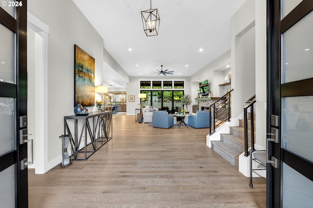 foyer with ceiling fan with notable chandelier and light wood-type flooring