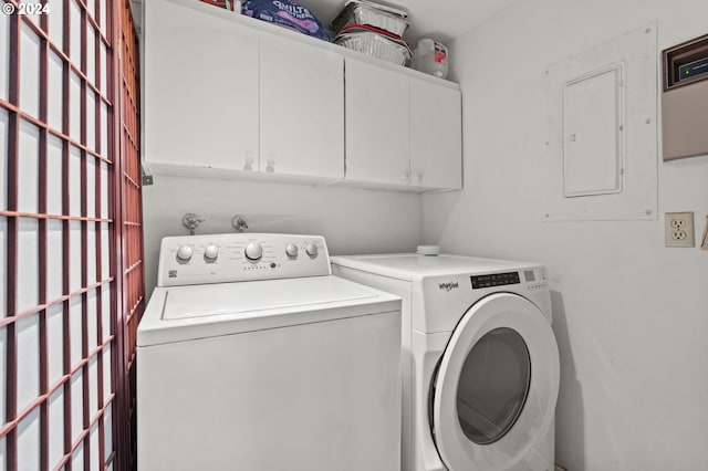 laundry room with electric panel, washer and clothes dryer, and cabinets