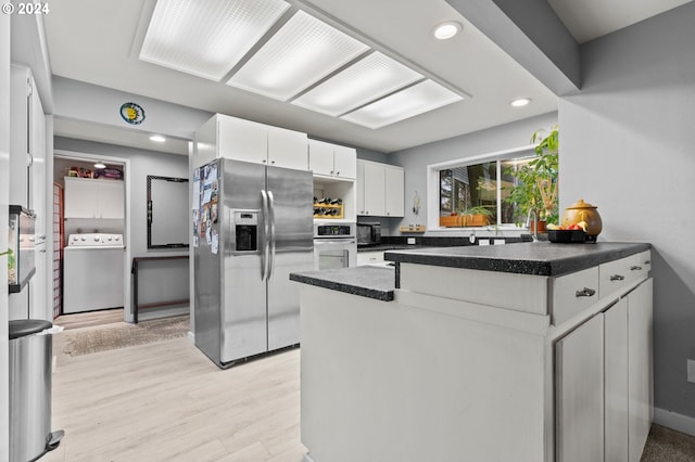 kitchen featuring stainless steel appliances, light hardwood / wood-style floors, kitchen peninsula, white cabinetry, and washer / dryer