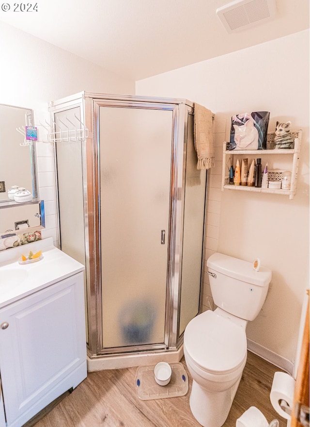 bathroom featuring vanity, toilet, hardwood / wood-style flooring, and walk in shower