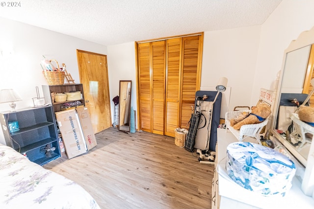 bedroom featuring a textured ceiling, light hardwood / wood-style flooring, and a closet