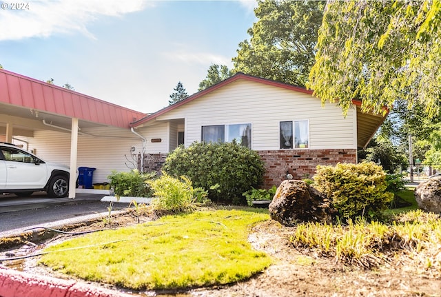 view of front of home with a carport, brick siding, and a front lawn