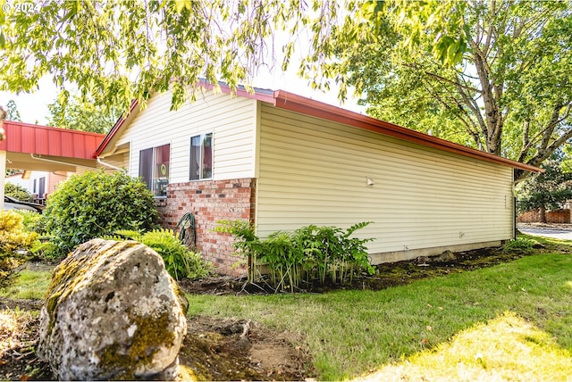 view of home's exterior with brick siding and a lawn