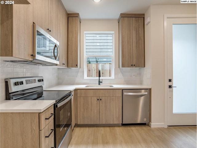 kitchen with backsplash, light wood-type flooring, and appliances with stainless steel finishes