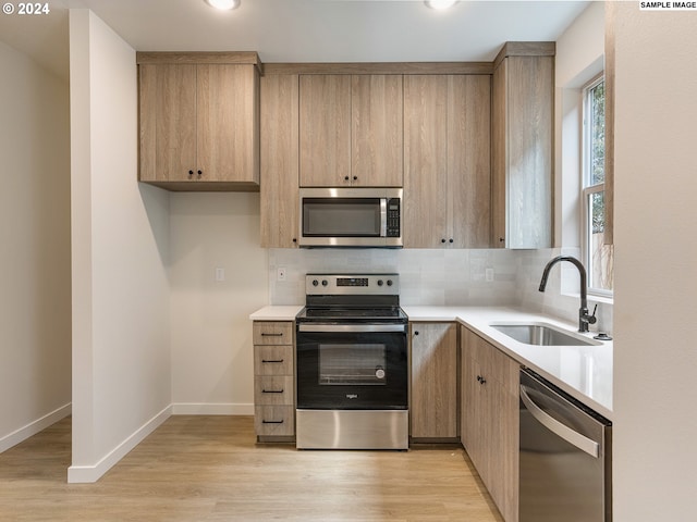 kitchen featuring backsplash, sink, appliances with stainless steel finishes, and light wood-type flooring