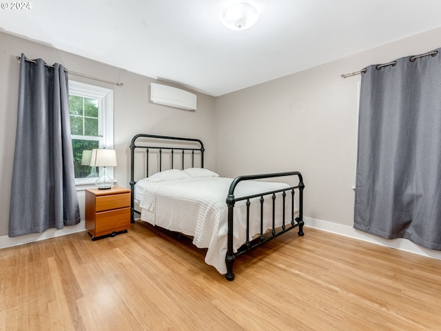 bedroom featuring a wall mounted air conditioner and light wood-type flooring