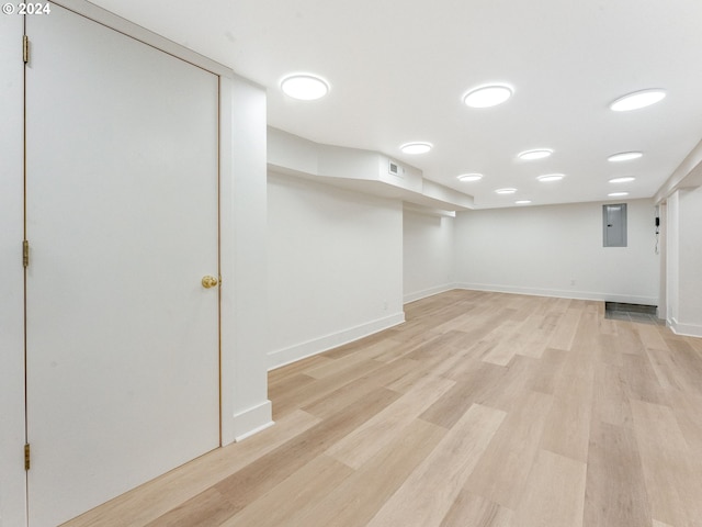 basement with light wood-type flooring and electric panel